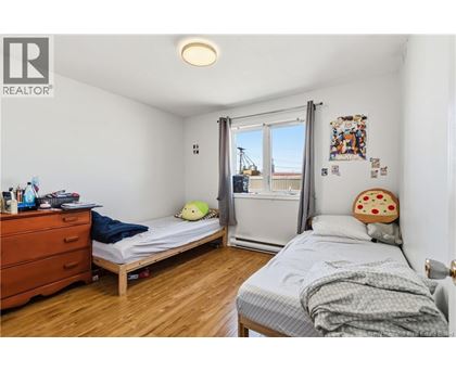 A bedroom with a bed, a dresser, and a window with a view of a construction site.