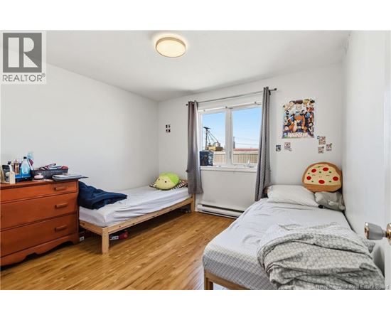 A bedroom with a bed, a dresser, and a window with a view of a construction site.