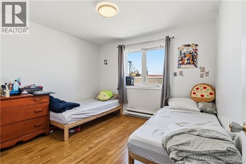 A bedroom with a bed, a dresser, and a window with a view of a construction site.