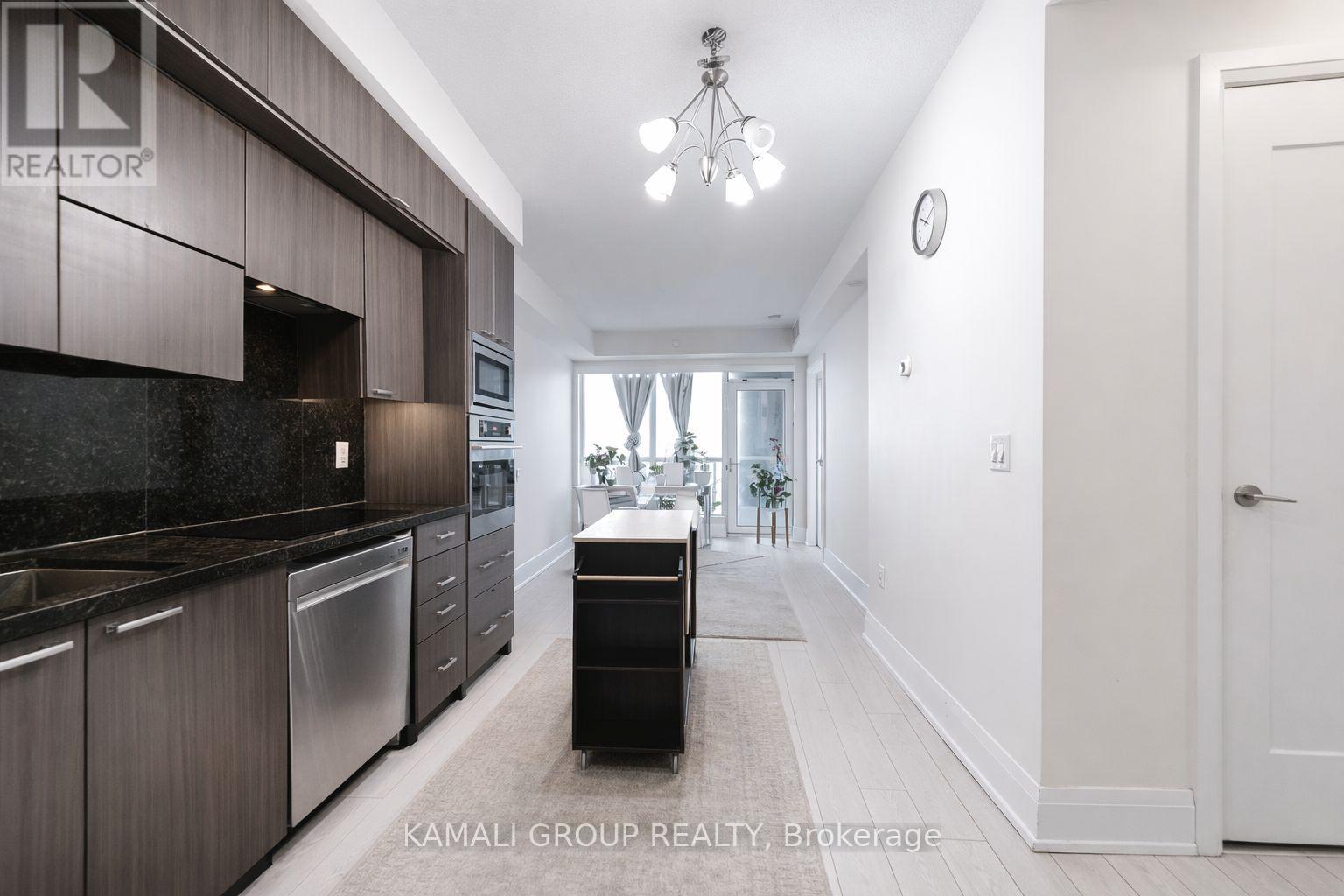 A modern kitchen with dark wood cabinets and stainless steel appliances.