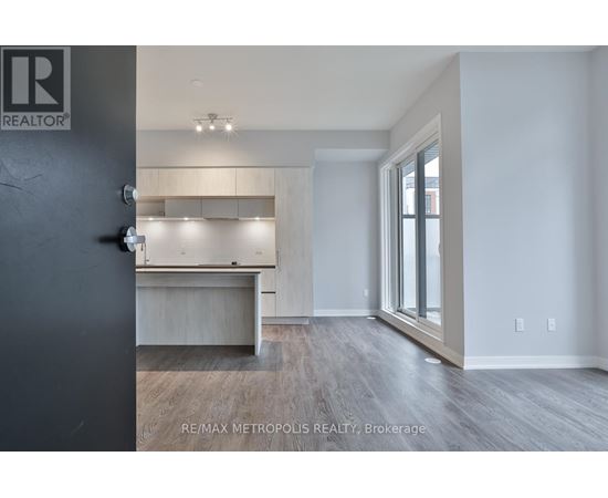 A room with a grey floor and white walls, with a black door on the left and a window on the right.