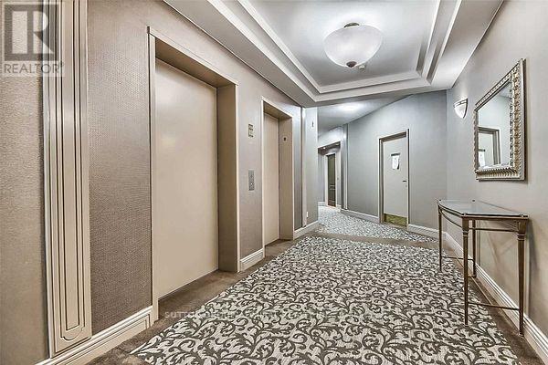 A hallway with a patterned floor and a mirror on the wall.