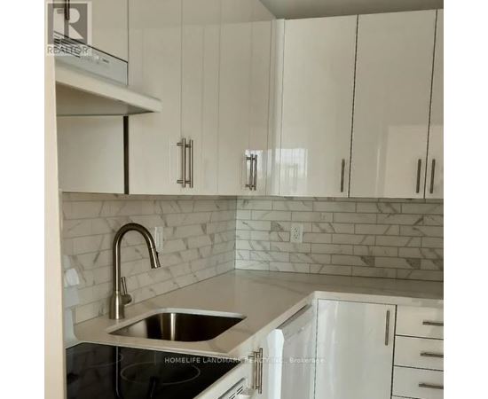 A kitchen with white cabinets and a marble backsplash.