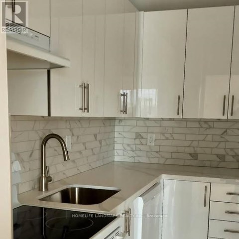A kitchen with white cabinets and a marble backsplash.