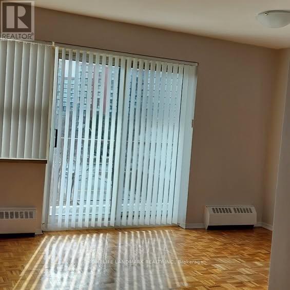 A room with a window covered by white blinds and a wooden floor.