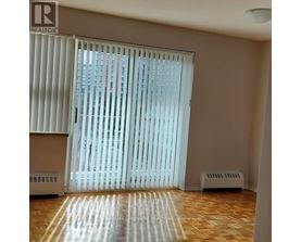 A room with a window covered by white blinds and a wooden floor.