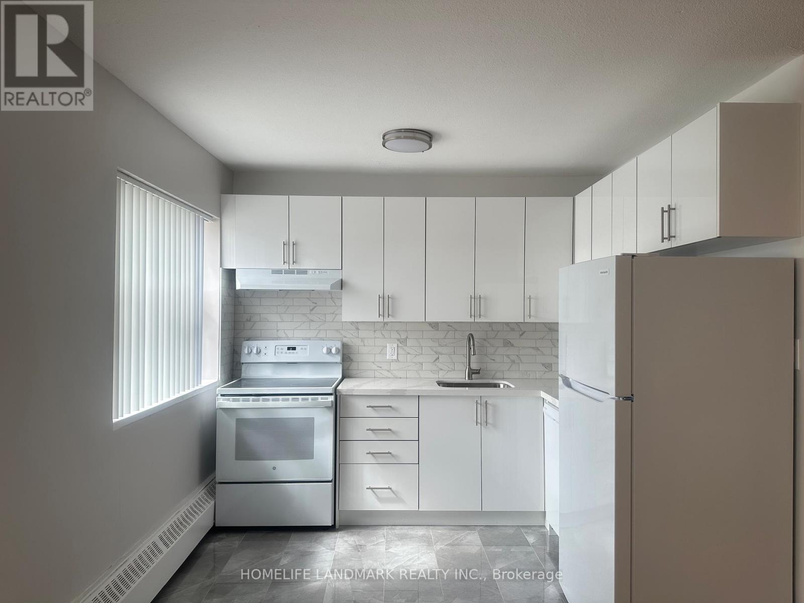A white kitchen with a stove, oven, and refrigerator.