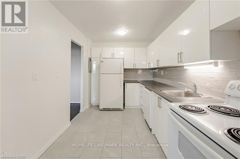 A white kitchen with a stove top oven and a sink.