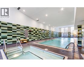 A swimming pool in a room with a green and black tiled wall.