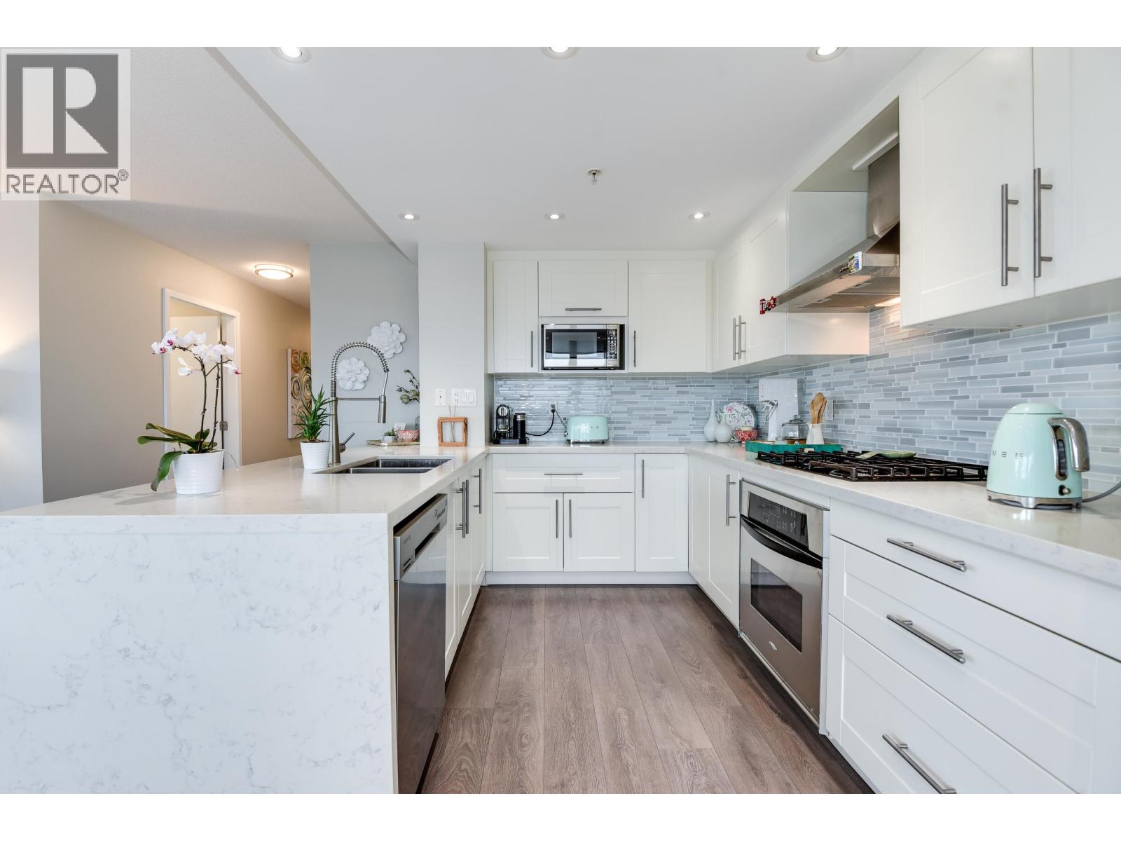A modern kitchen with white cabinets and a marble countertop.