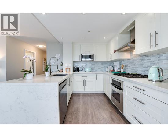 A modern kitchen with white cabinets and a marble countertop.