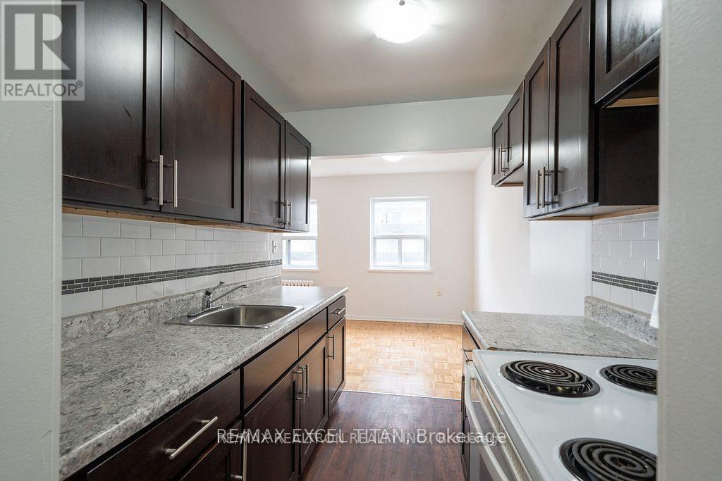 A kitchen with dark wood cabinets and a white stove top oven.