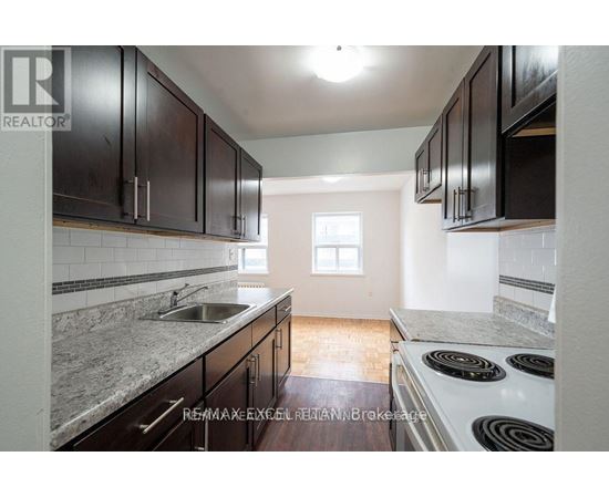 A kitchen with dark wood cabinets and a white stove top oven.