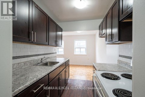 A kitchen with dark wood cabinets and a white stove top oven.