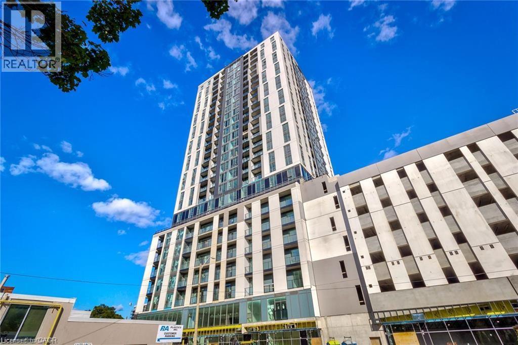 A tall building with a glass facade stands next to a smaller building with a concrete facade.