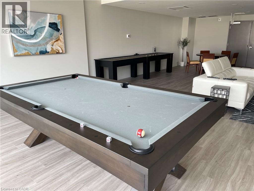 A pool table in a room with a painting on the wall and a sofa in the background.