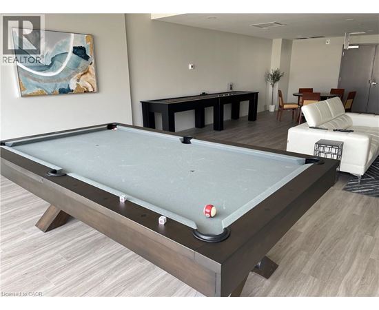 A pool table in a room with a painting on the wall and a sofa in the background.
