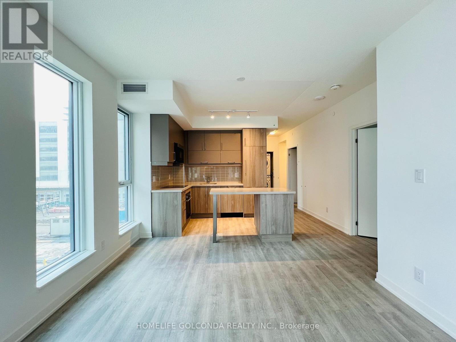 A spacious, well-lit kitchen and living room with a large island in the middle.