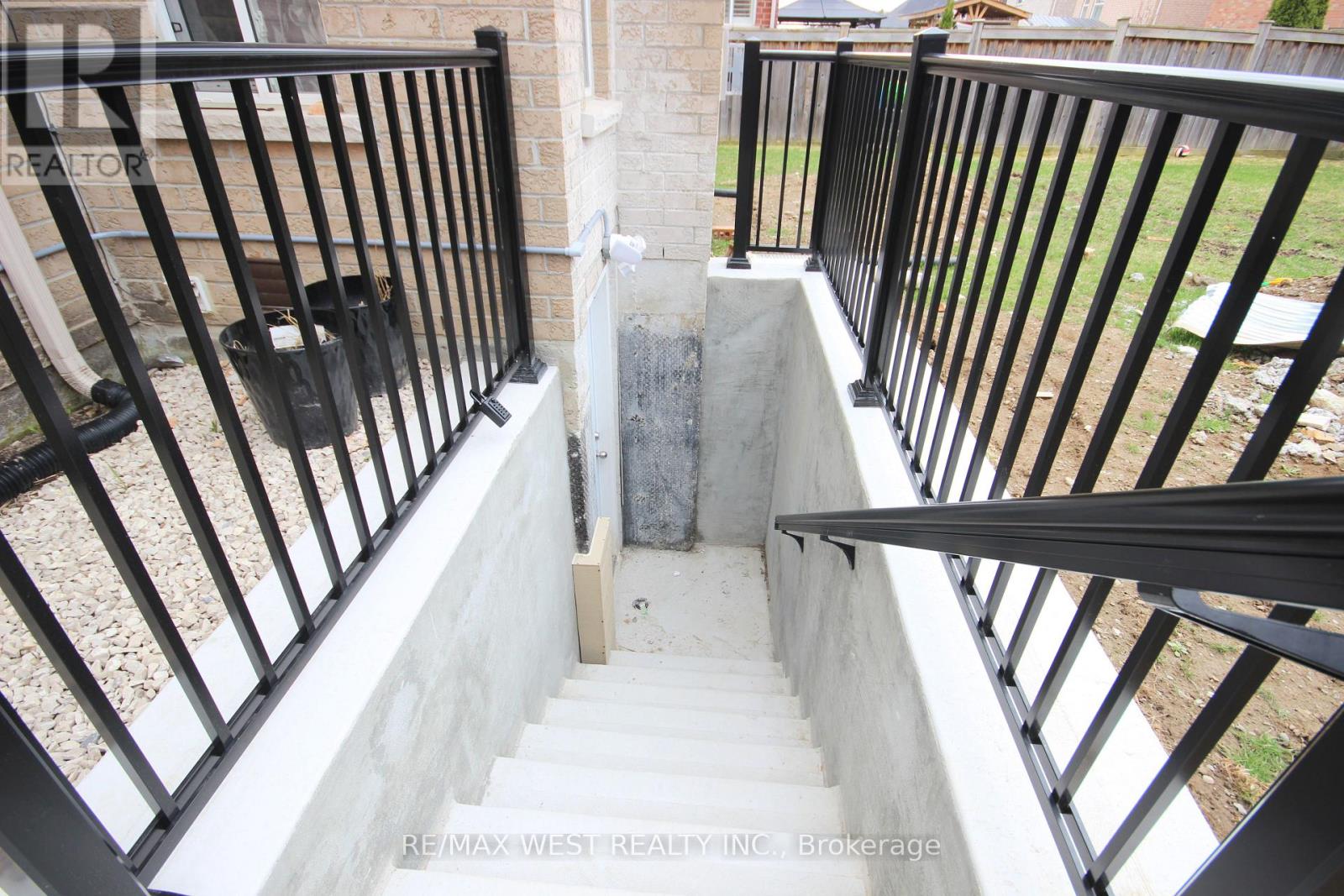 A staircase with a black railing and a concrete step.