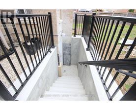 A staircase with a black railing and a concrete step.
