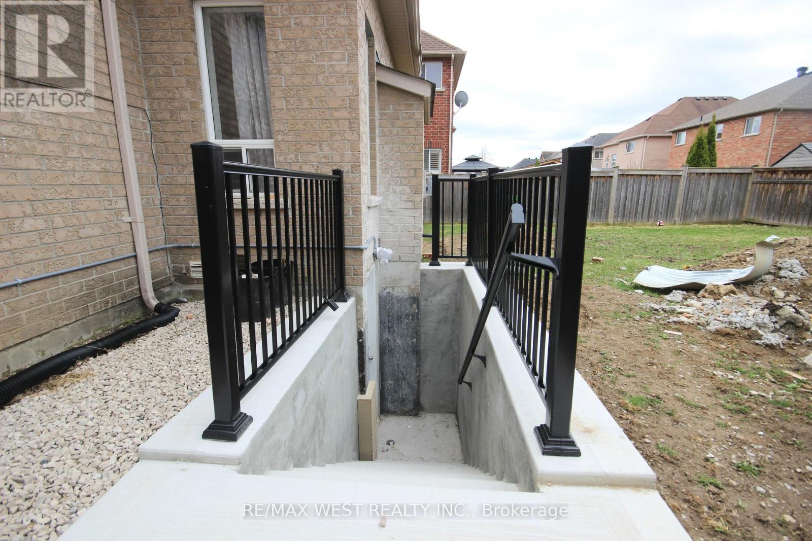 A black metal fence with a gate is in front of a brick house.