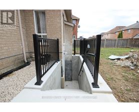 A black metal fence with a gate is in front of a brick house.