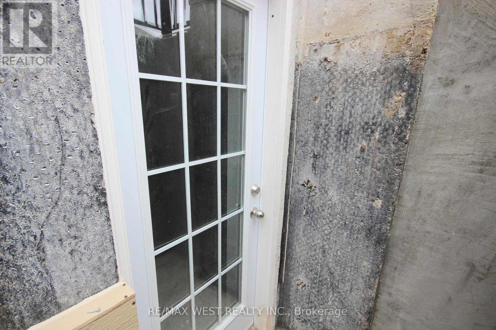 A white door with a glass panel is set in a concrete wall.
