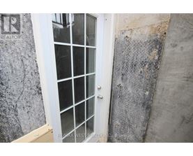 A white door with a glass panel is set in a concrete wall.