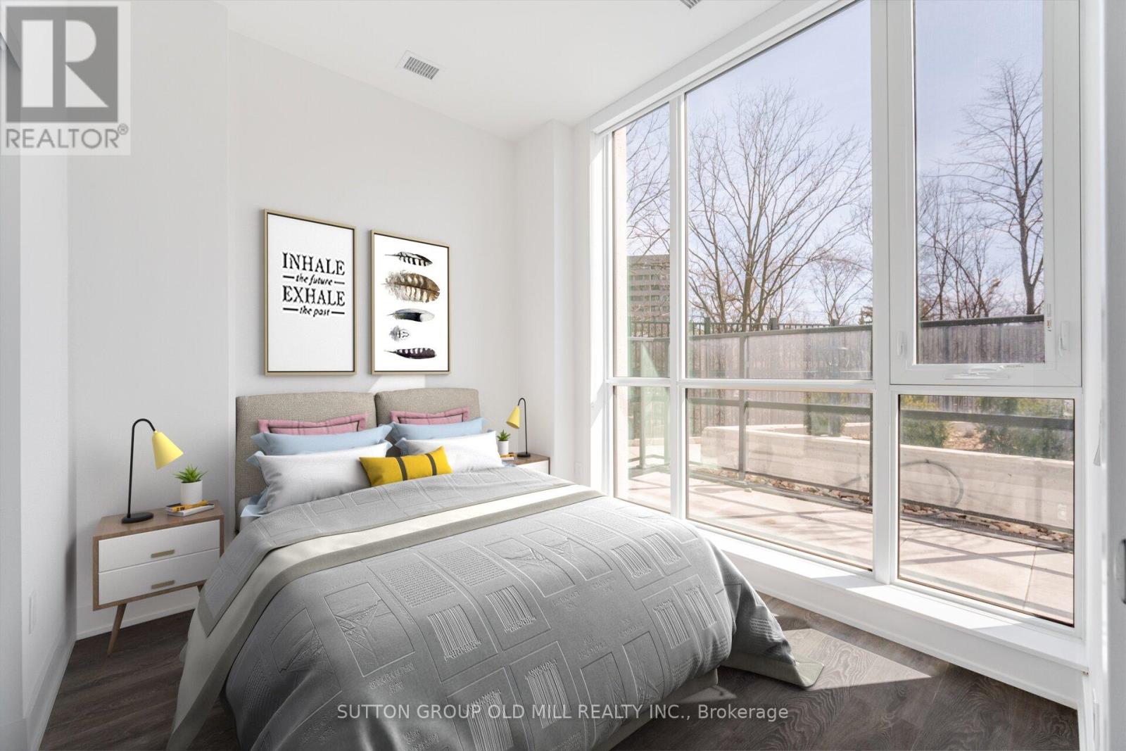 A bedroom with a large bed and a window overlooking a fence.
