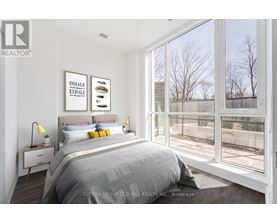 A bedroom with a large bed and a window overlooking a fence.