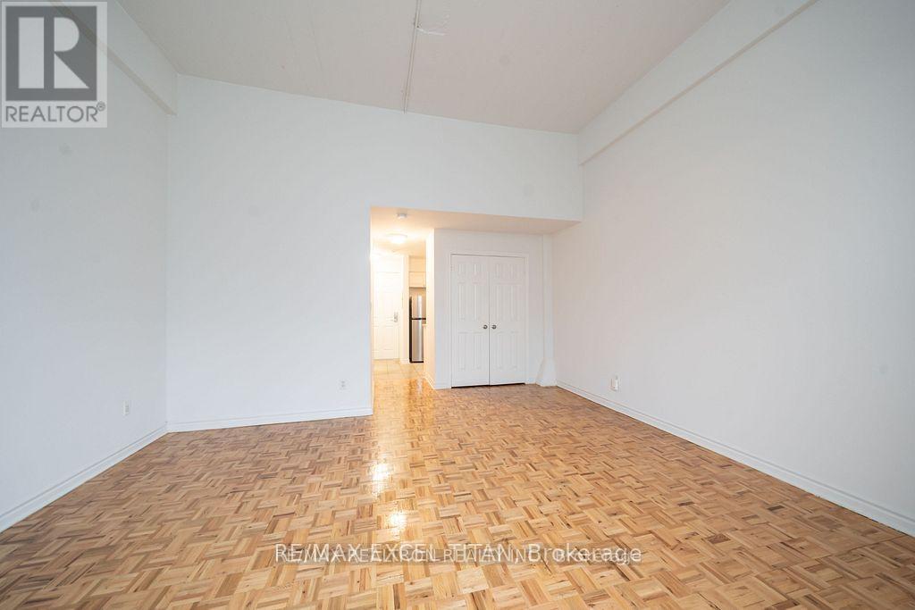 A room with wooden flooring and white walls, with a door at the end of the room.
