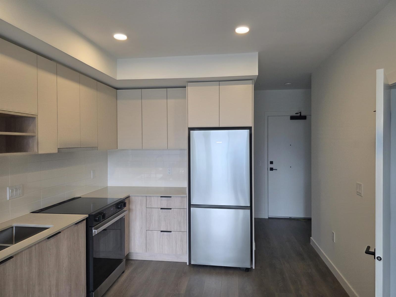 A kitchen with a refrigerator, oven, and sink.