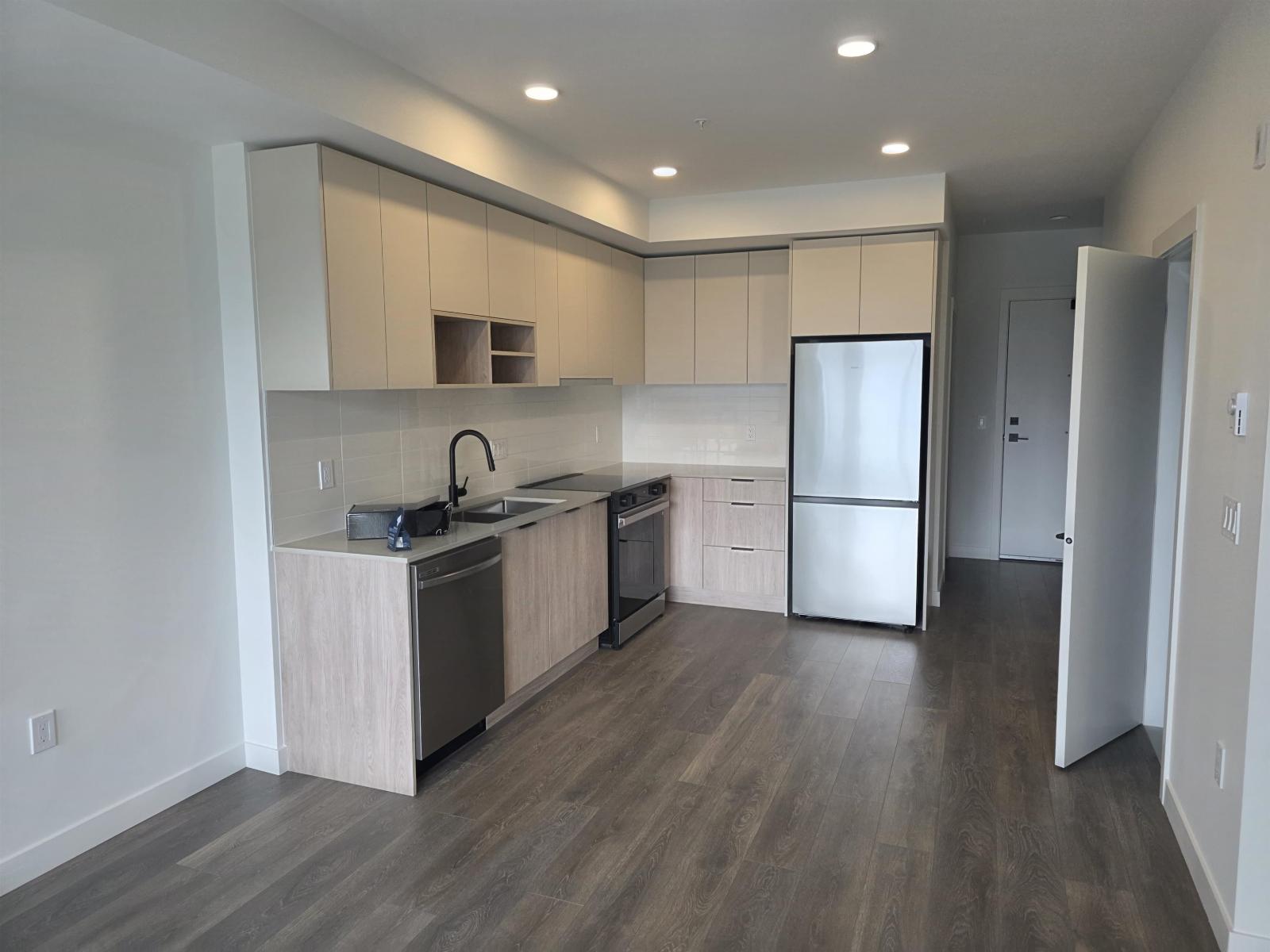 A modern kitchen with wooden floors and stainless steel appliances.