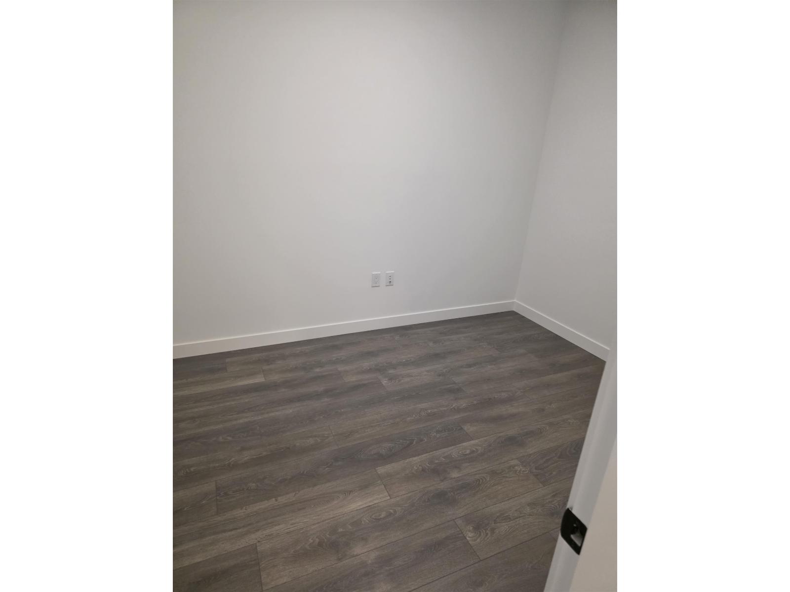 A room with a wooden floor and a white wall.