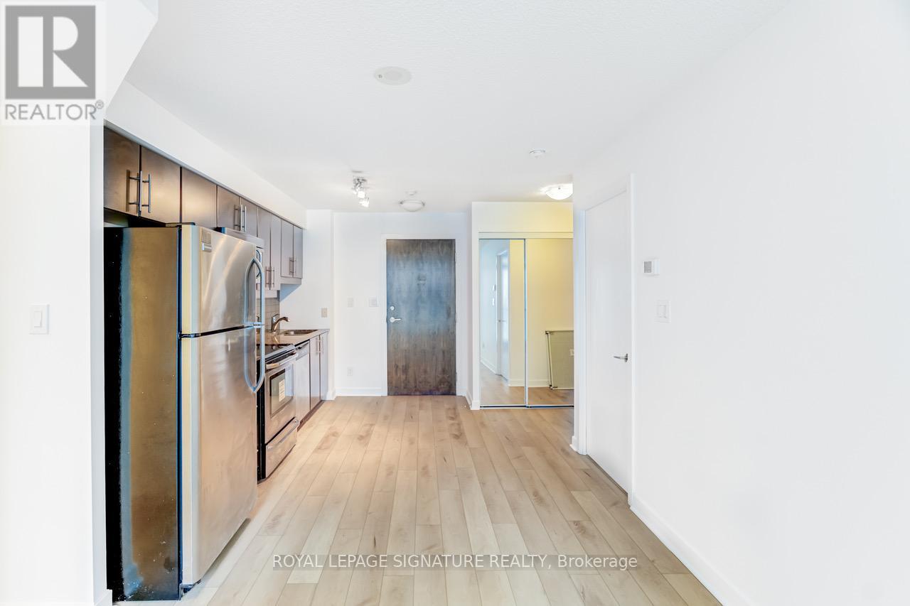 A kitchen with a refrigerator, cabinets, and a countertop.