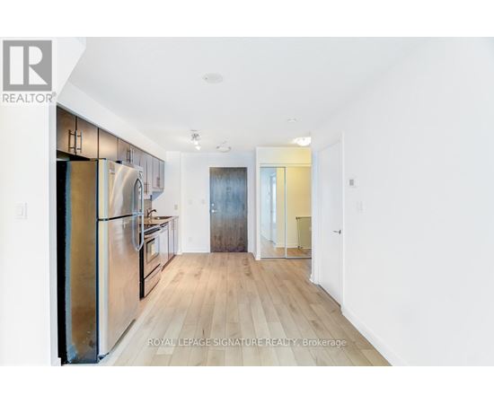 A kitchen with a refrigerator, cabinets, and a countertop.