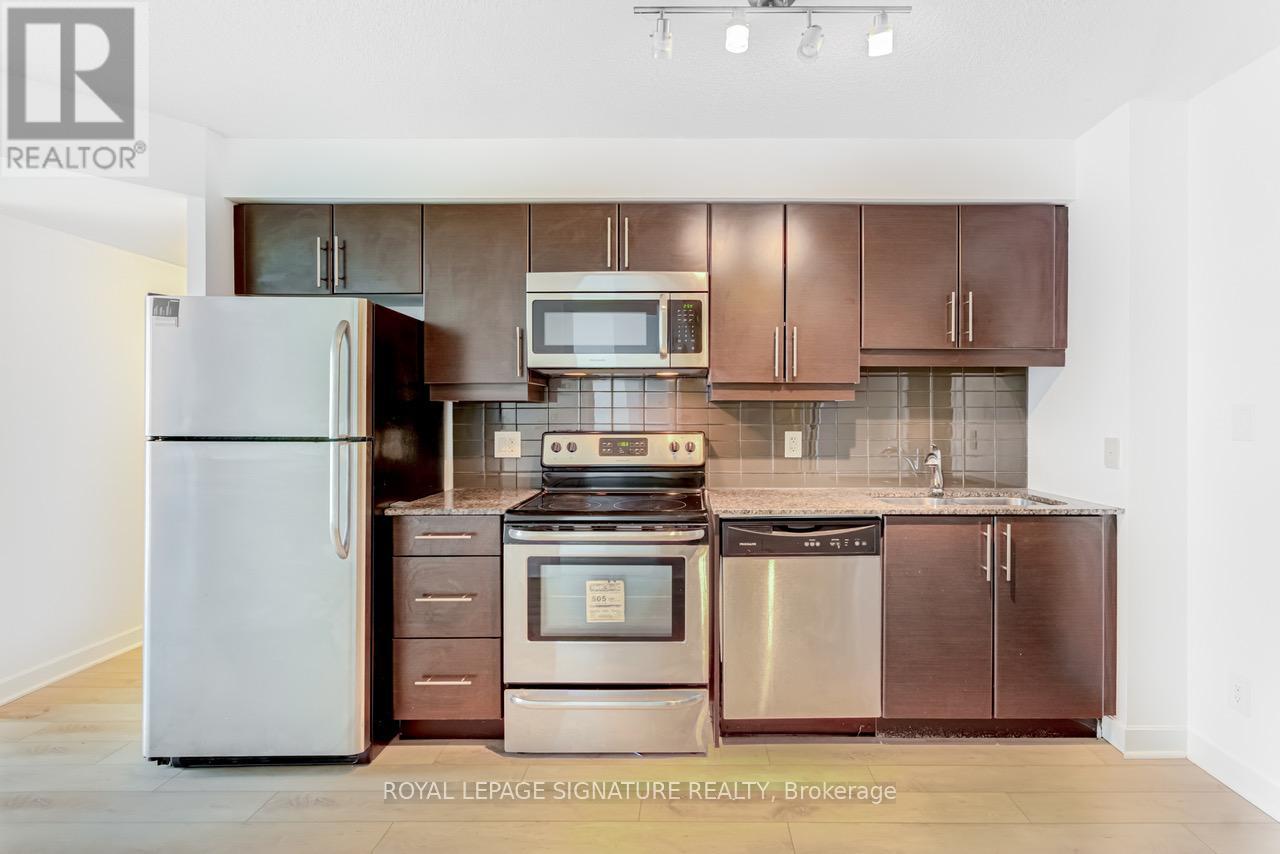 A kitchen with a refrigerator, oven, and microwave.