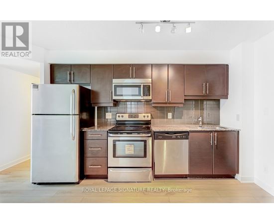 A kitchen with a refrigerator, oven, and microwave.