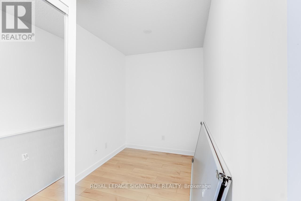 A white room with a wooden floor and a door on the left.