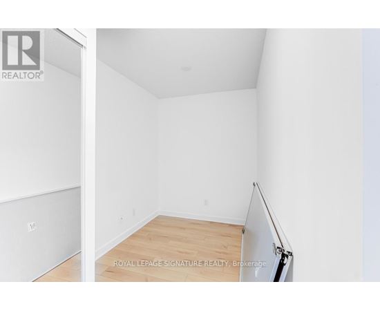 A white room with a wooden floor and a door on the left.