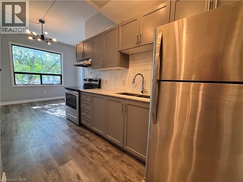 A modern kitchen with a stainless steel refrigerator and wooden flooring.