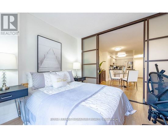 A bedroom with a large bed and a picture of a pyramid on the wall.