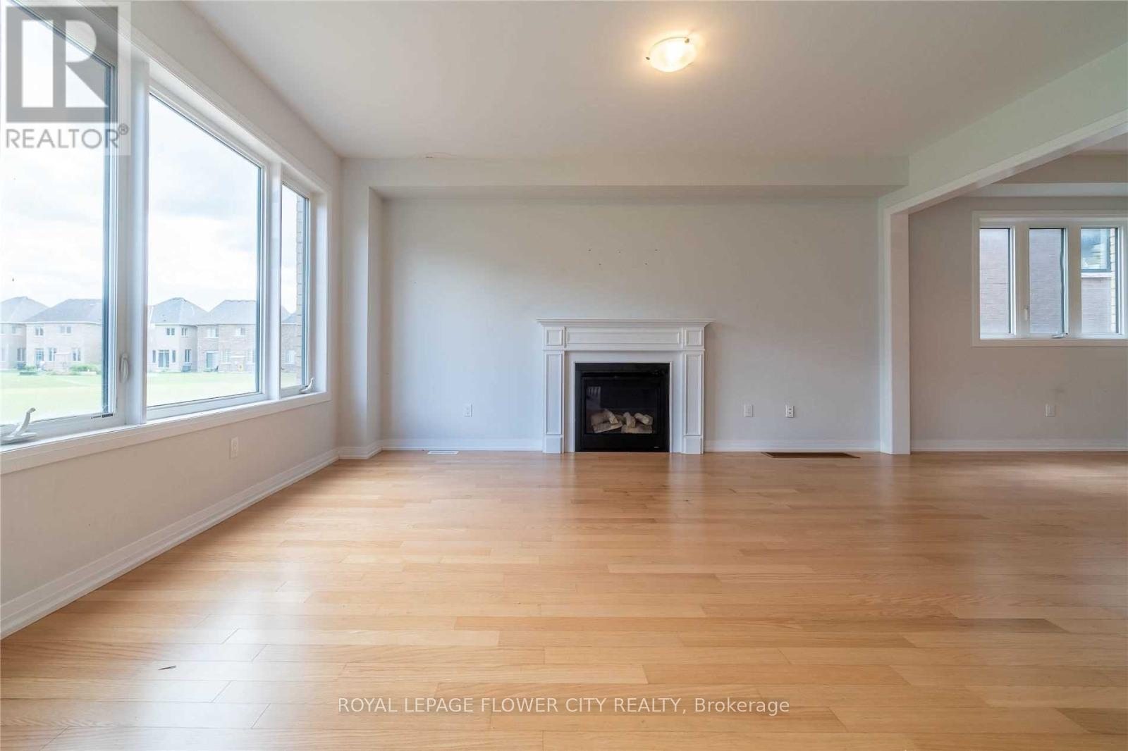A spacious room with a fireplace and wooden floors.