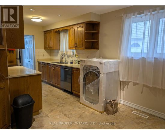 A kitchen with wooden cabinets and a black trash can.