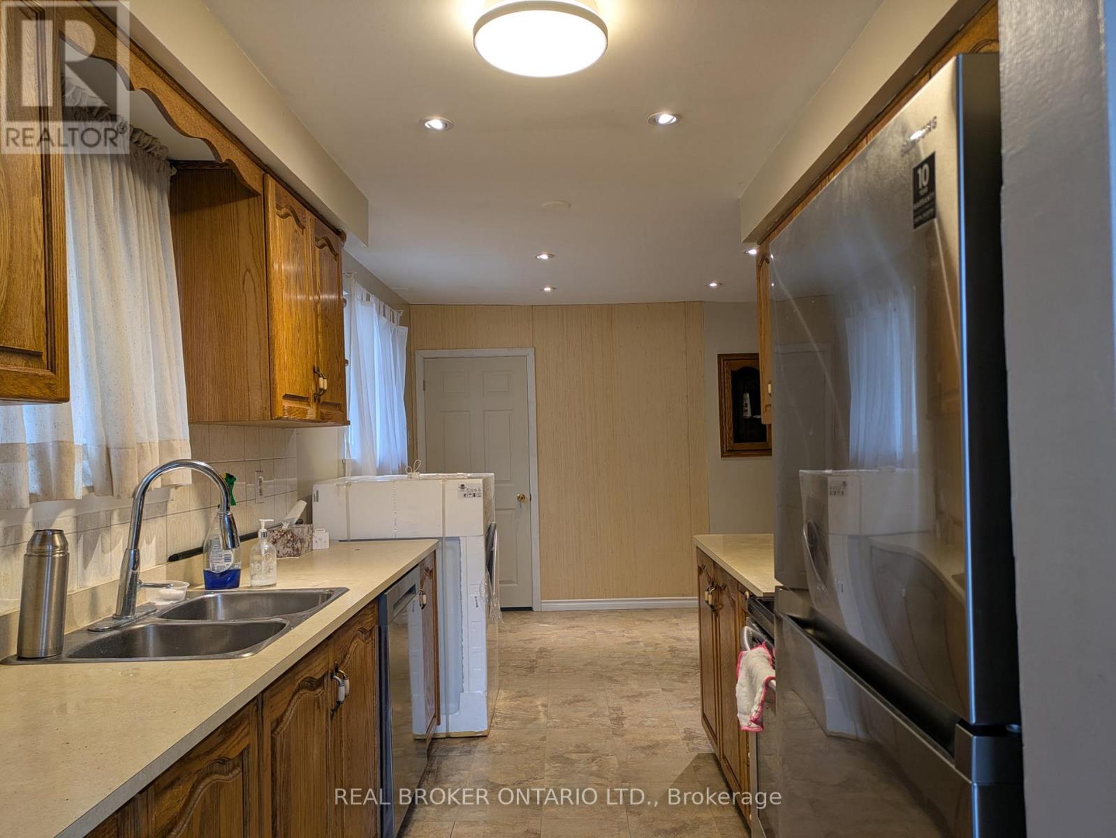 A kitchen with wooden cabinets and a stainless steel refrigerator.