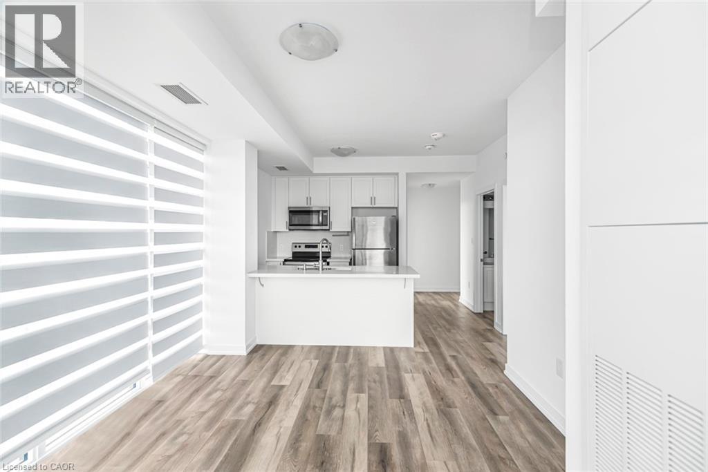 A modern kitchen with white cabinets and a wooden floor.