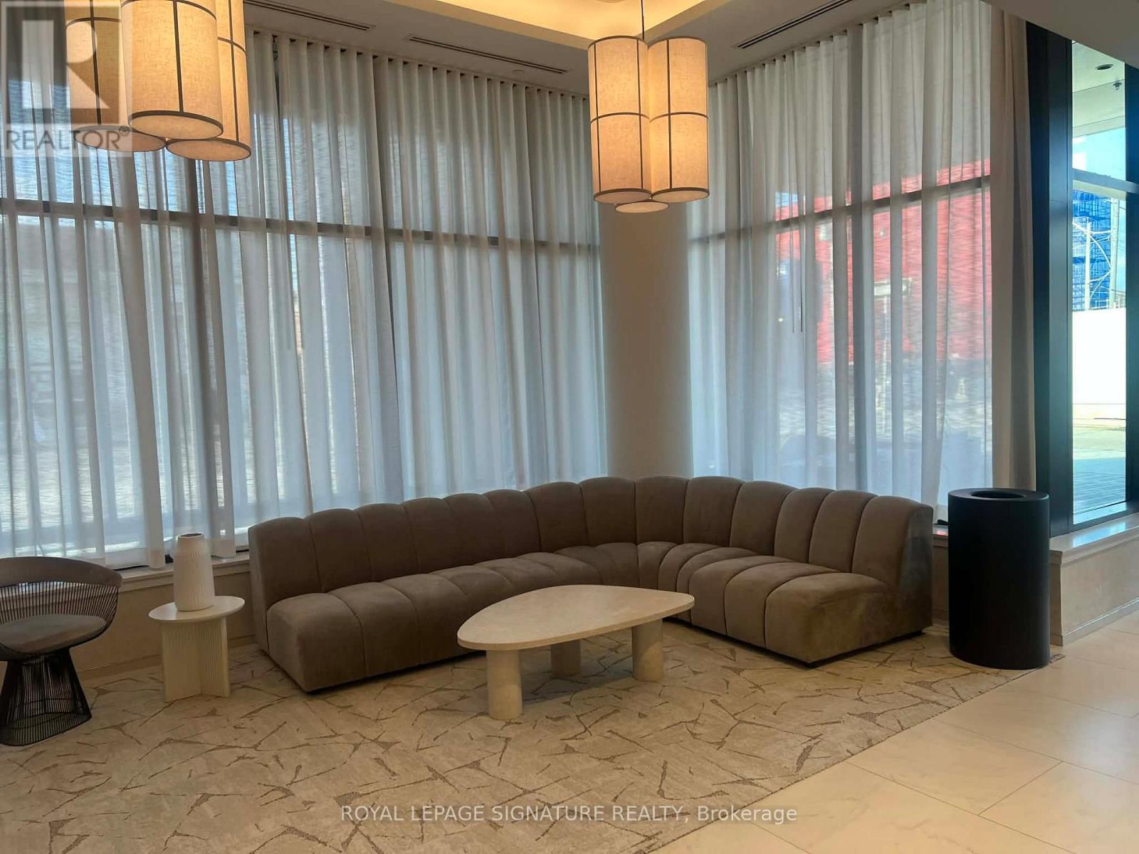 A living room with a large couch, a coffee table, and two lamps.