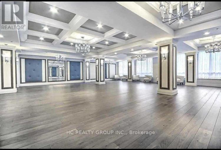 A spacious room with wooden floors and a chandelier.