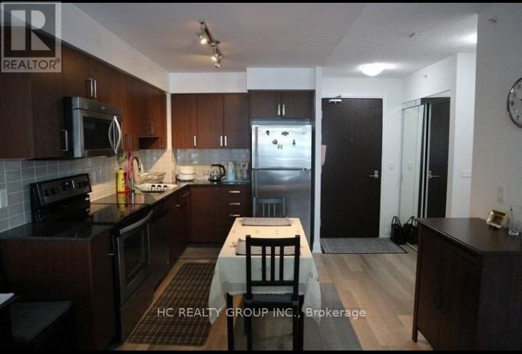 A kitchen with dark wood cabinets and a black refrigerator.