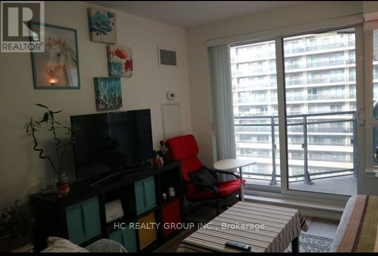 A living room with a flat screen TV, a red chair, and a large window.